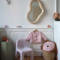 Children's room with ecoBirdy Marine Mirror Faded-White and Charlie Chair in strawberry colour way, a pink floral coat, and lion-shaped cushion.